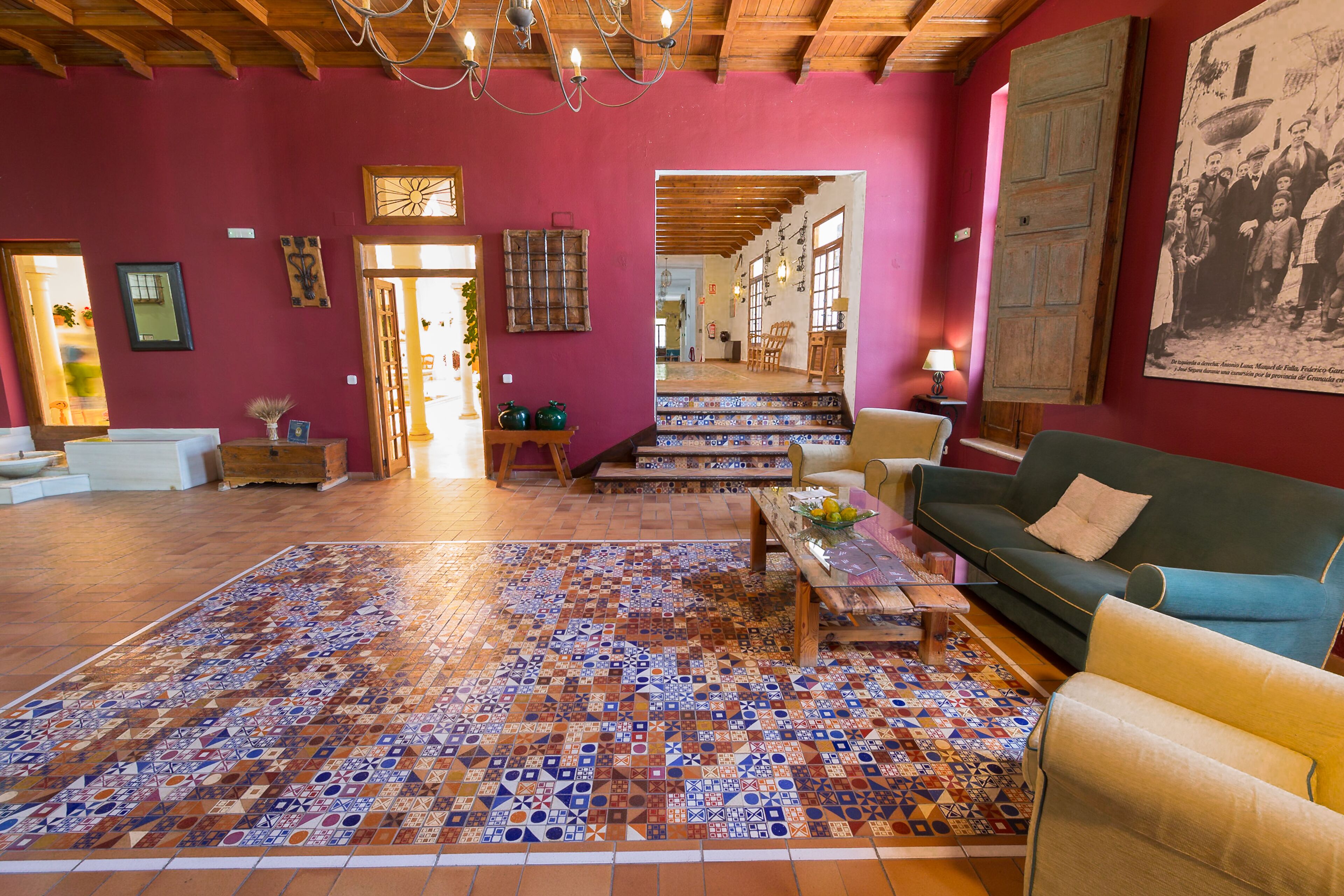 Un salon spacieux agrémenté d’un tapis à motifs, d’un canapé vert et d’une table basse en bois.