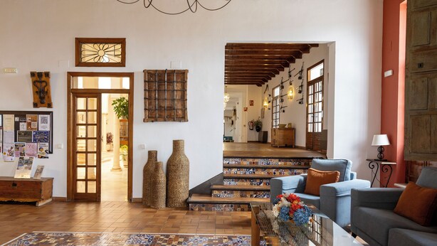 A spacious living room with a patterned rug, a sofa, a coffee table, and a staircase leading to another level. - Villa Turística de Priego de Córdoba (Priego de Córdoba)