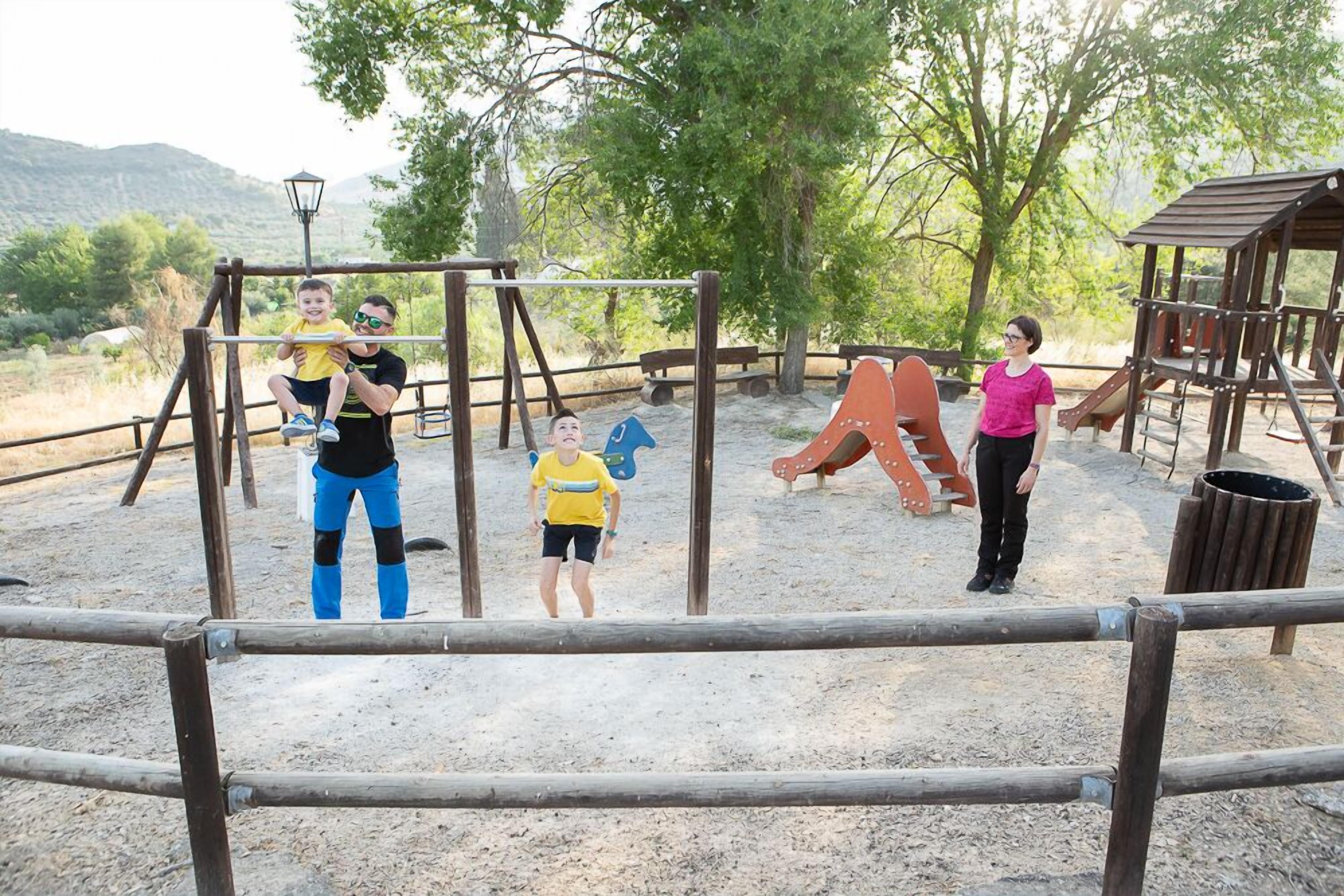A playground with swings, slides, and a wooden playhouse.