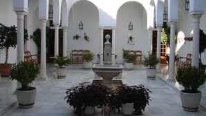 A courtyard with white columns, potted plants, and a central fountain. - Villa Turística de Priego de Córdoba (Priego de Córdoba)