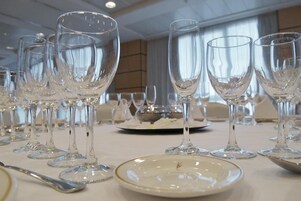 Una mesa dispuesta con varias copas de vino y platos, indicando una disposición formal para cenar.