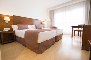A hotel room with a large bed, bedside tables, a desk, and a chair.