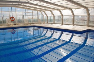 Una piscina cubierta, una piscina al aire libre, tumbonas