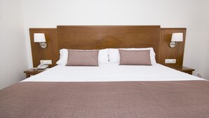 A neatly made bed with a wooden headboard, two bedside lamps, and a telephone on the nightstand. - Hotel Albufera (Alfafar)