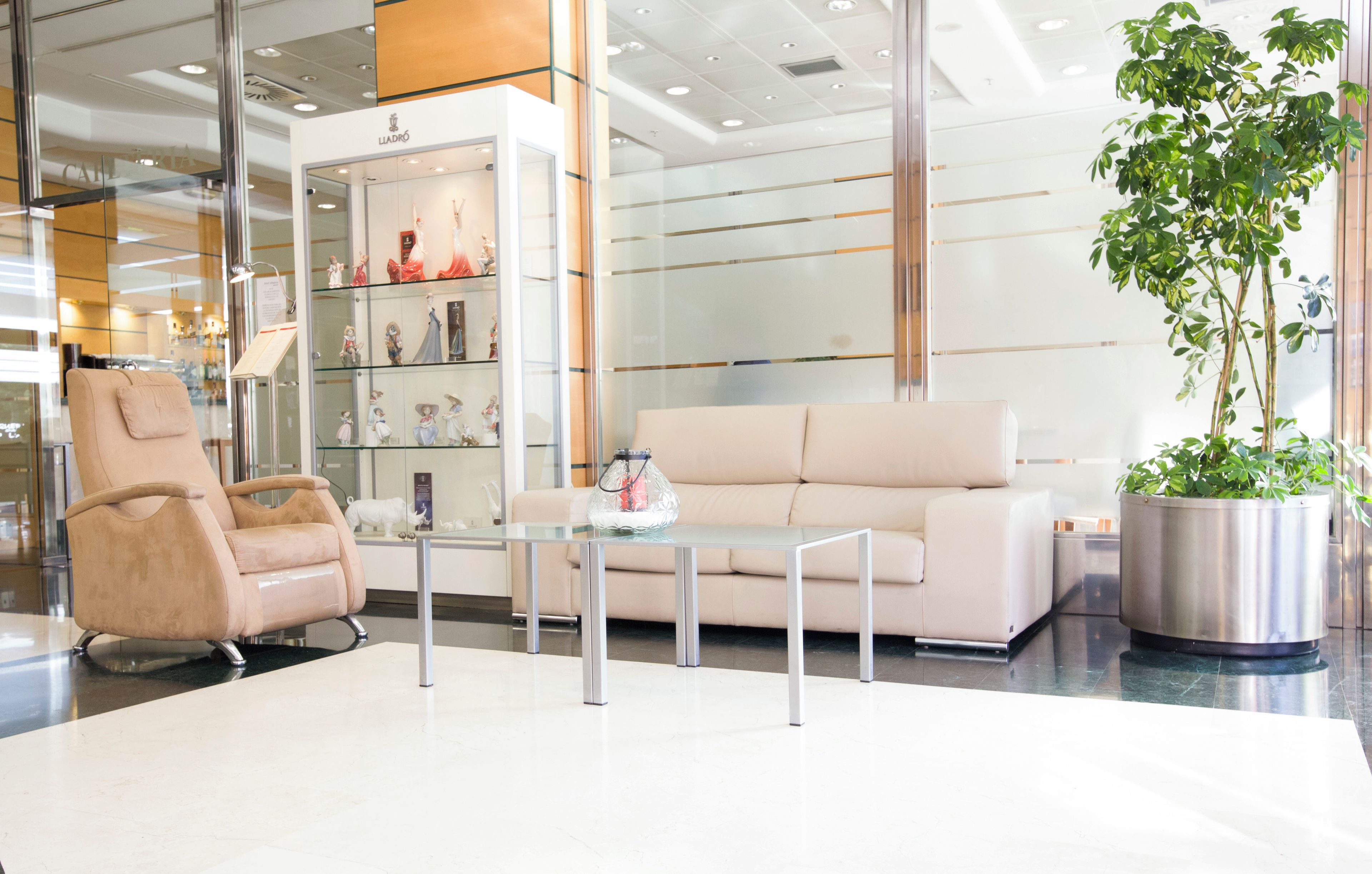 A modern interior with a beige sofa, a glass coffee table, and a beige armchair.