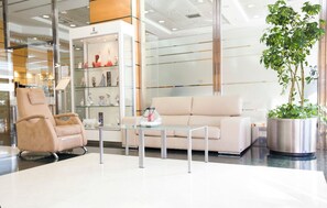 A modern interior with a beige sofa, a glass coffee table, and a beige armchair.