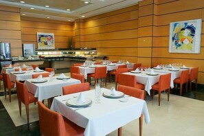 A dining area with multiple tables set for service, a buffet line, and a large abstract painting on the wall. - Hotel Albufera (Alfafar)