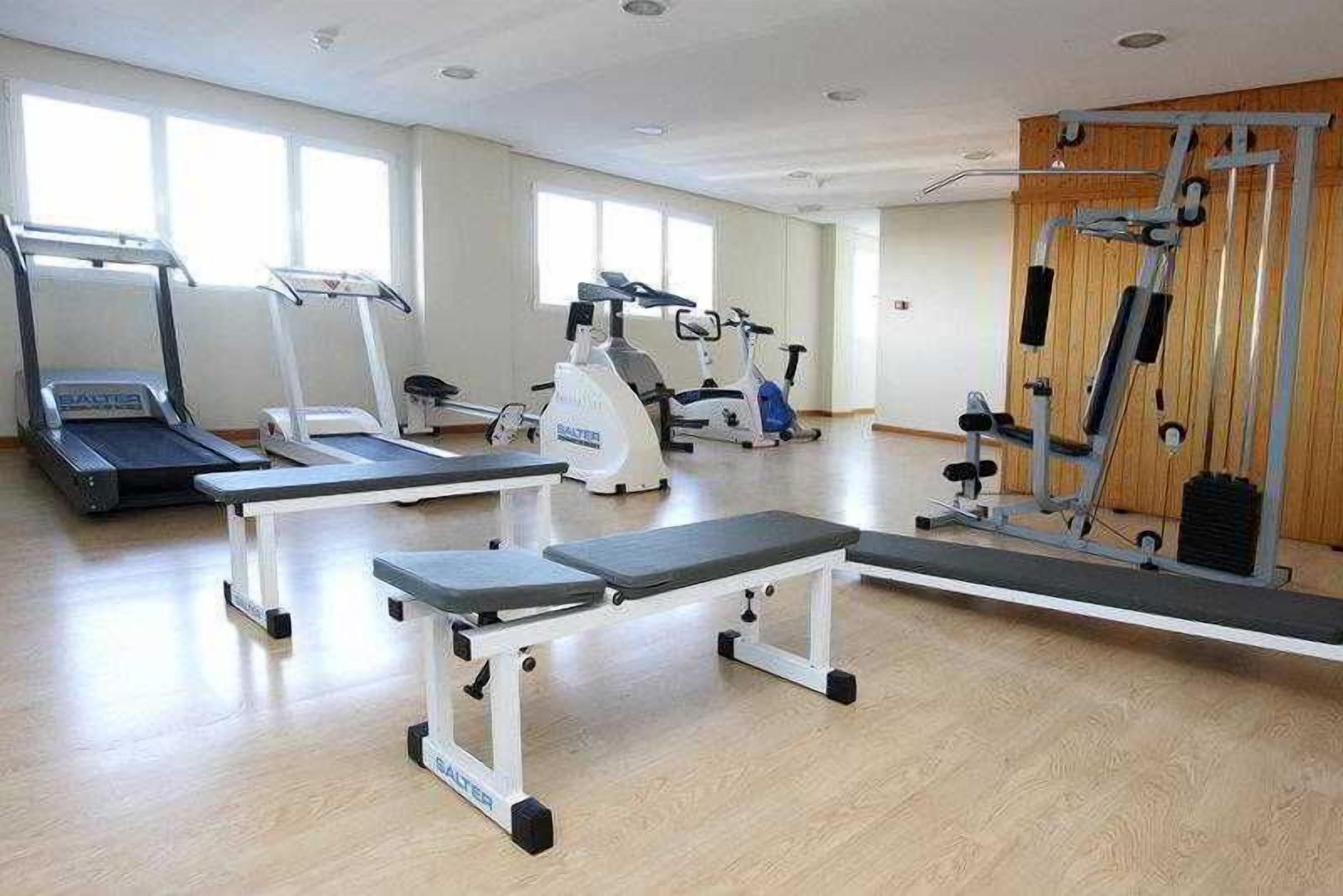 Un gimnasio con cintas de correr, elípticas y equipo de levantamiento de pesas.