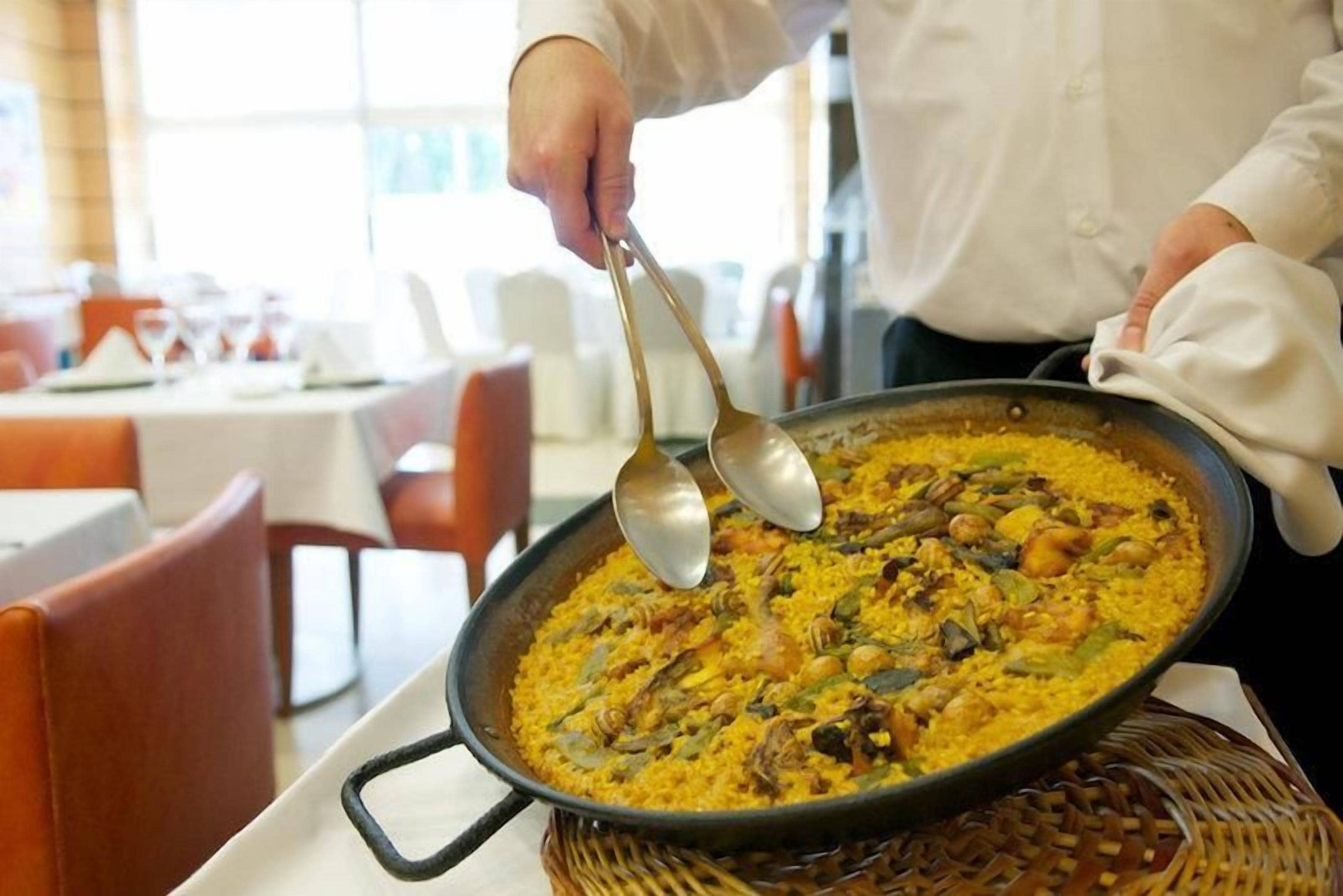 Una persona sirviendo una bandeja grande de comida en un restaurante.