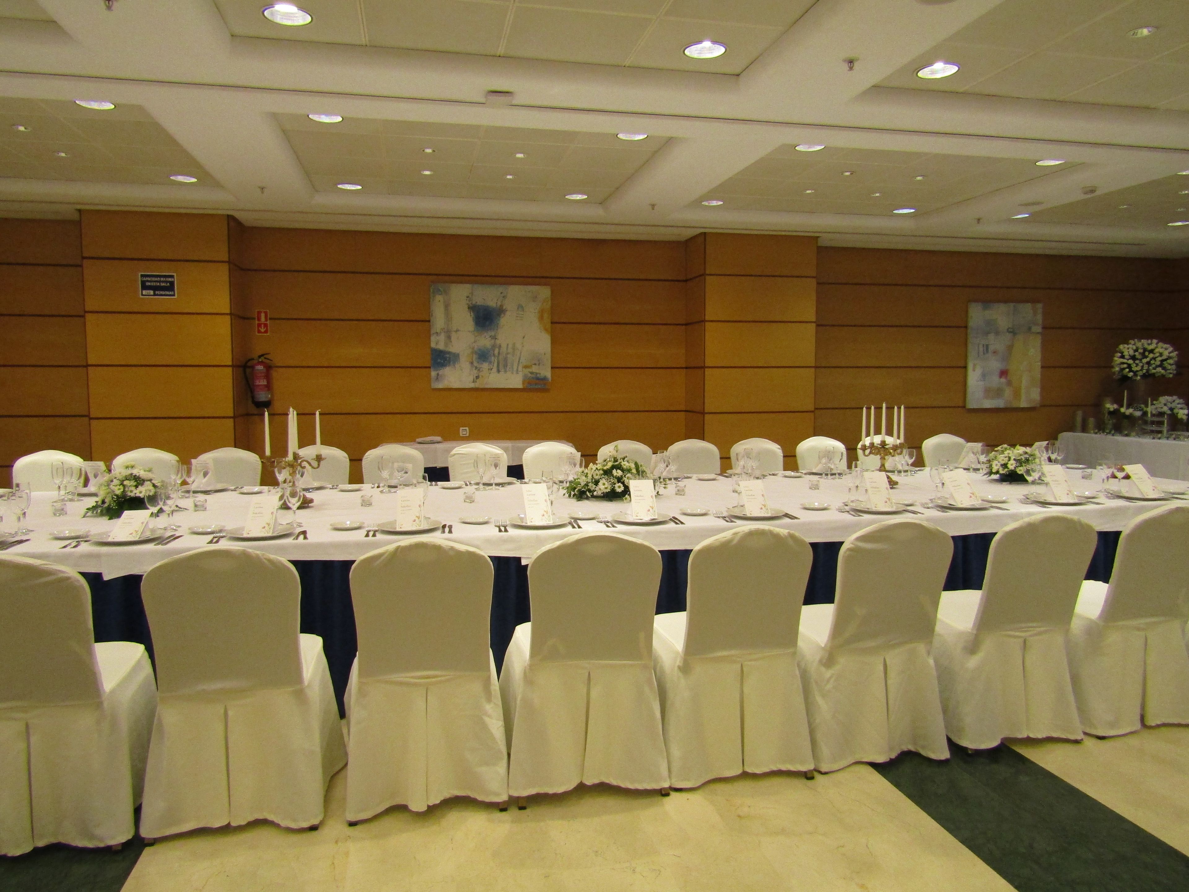 A banquet hall with long tables set for a formal event, white chairs, and a clean, modern interior.