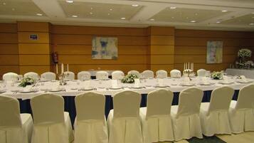 A banquet hall with long tables set for a formal event, white chairs, and a clean, modern interior.