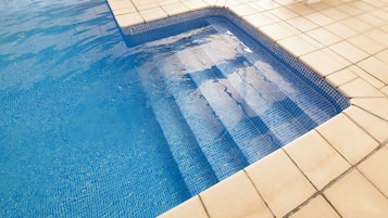 Ein Schwimmbecken mit klarem, blauem Wasser und einer gefliesten Liegefläche.