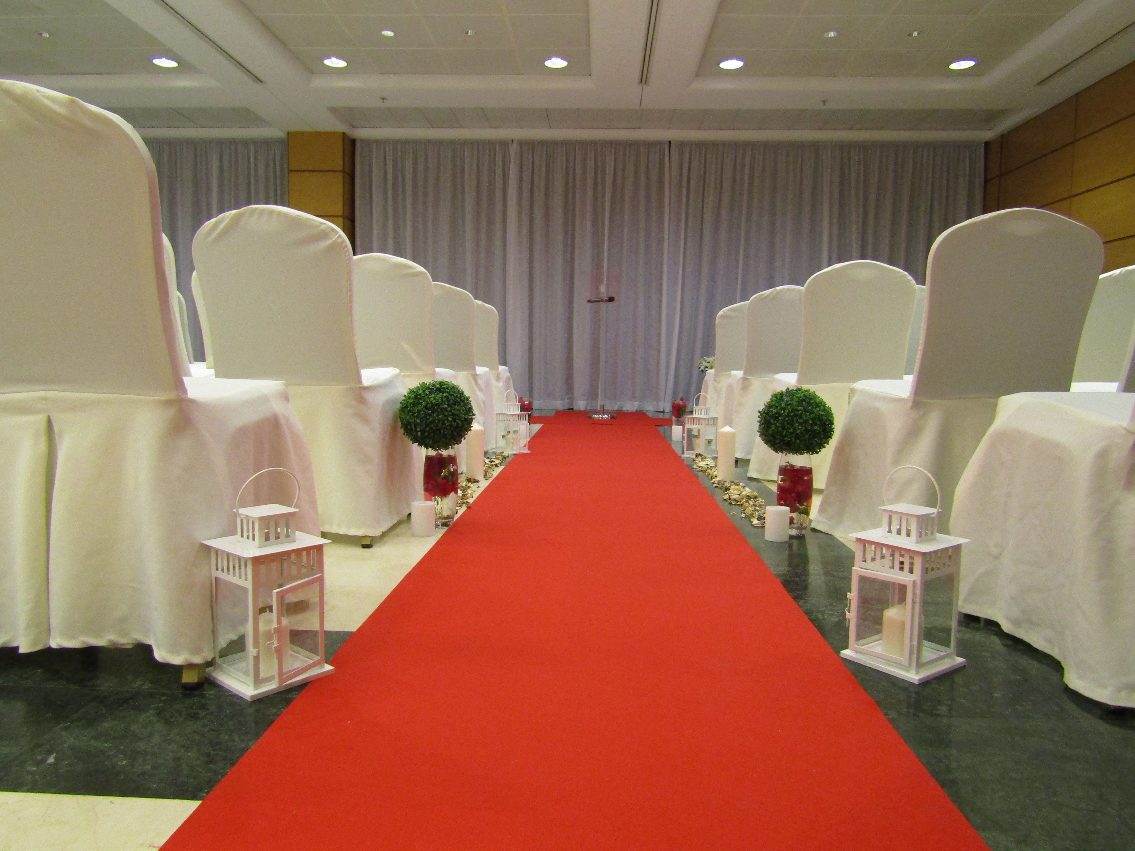 A red carpet aisle leading to a stage with white chairs on either side.