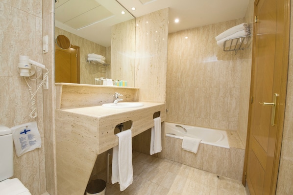 Un baño moderno con lavamanos de mármol, bañera y tocador con espejo.