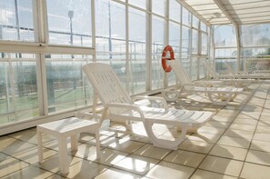 Una piscina cubierta, una piscina al aire libre, tumbonas