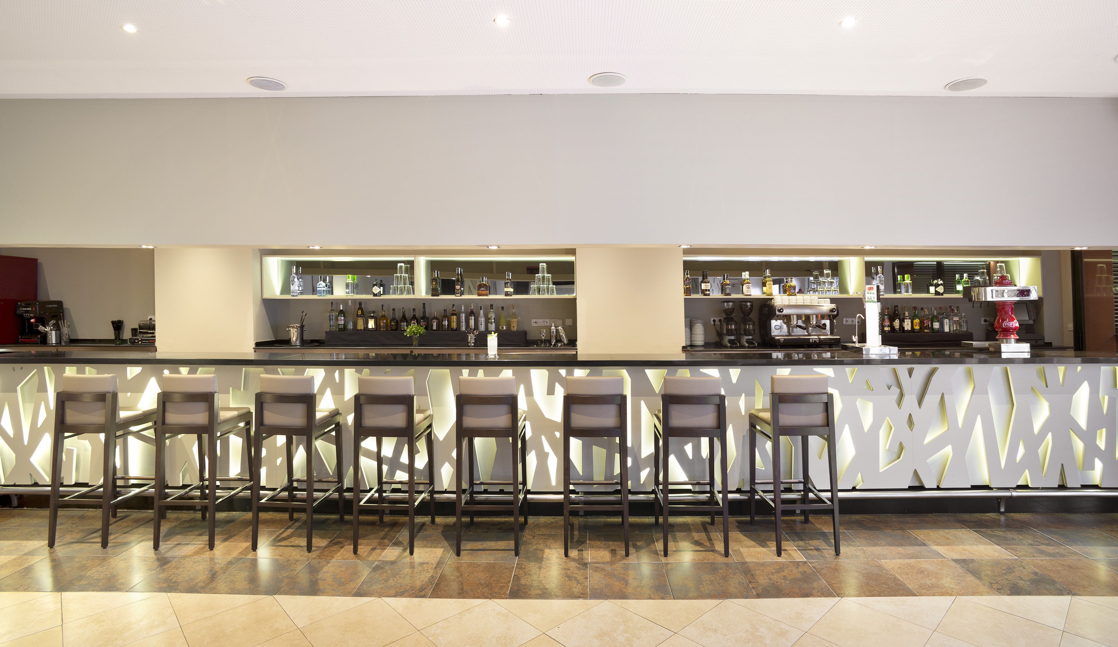 Zona de bar con mostrador, taburetes y estanterías llenas de bebidas.