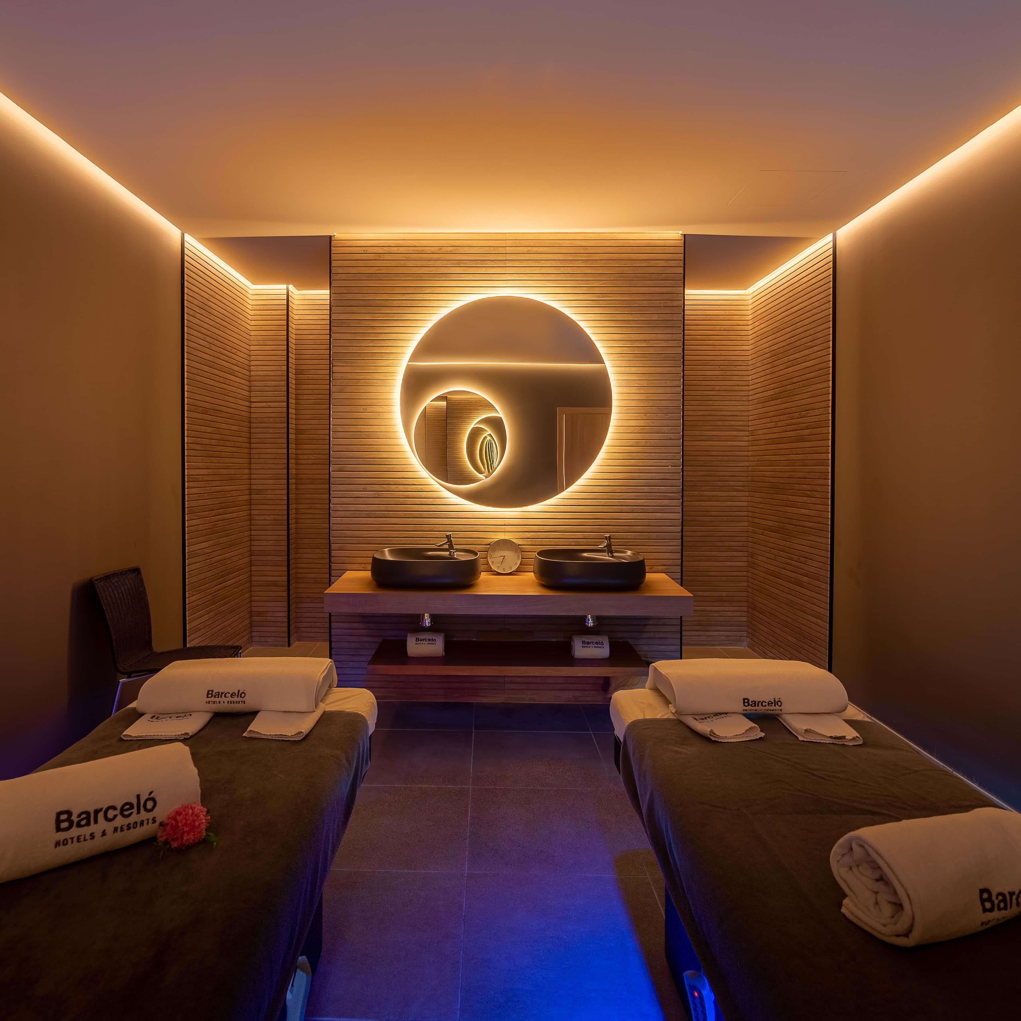 Un cuarto de spa con dos camas, un elemento decorativo circular en la pared y un minibar.