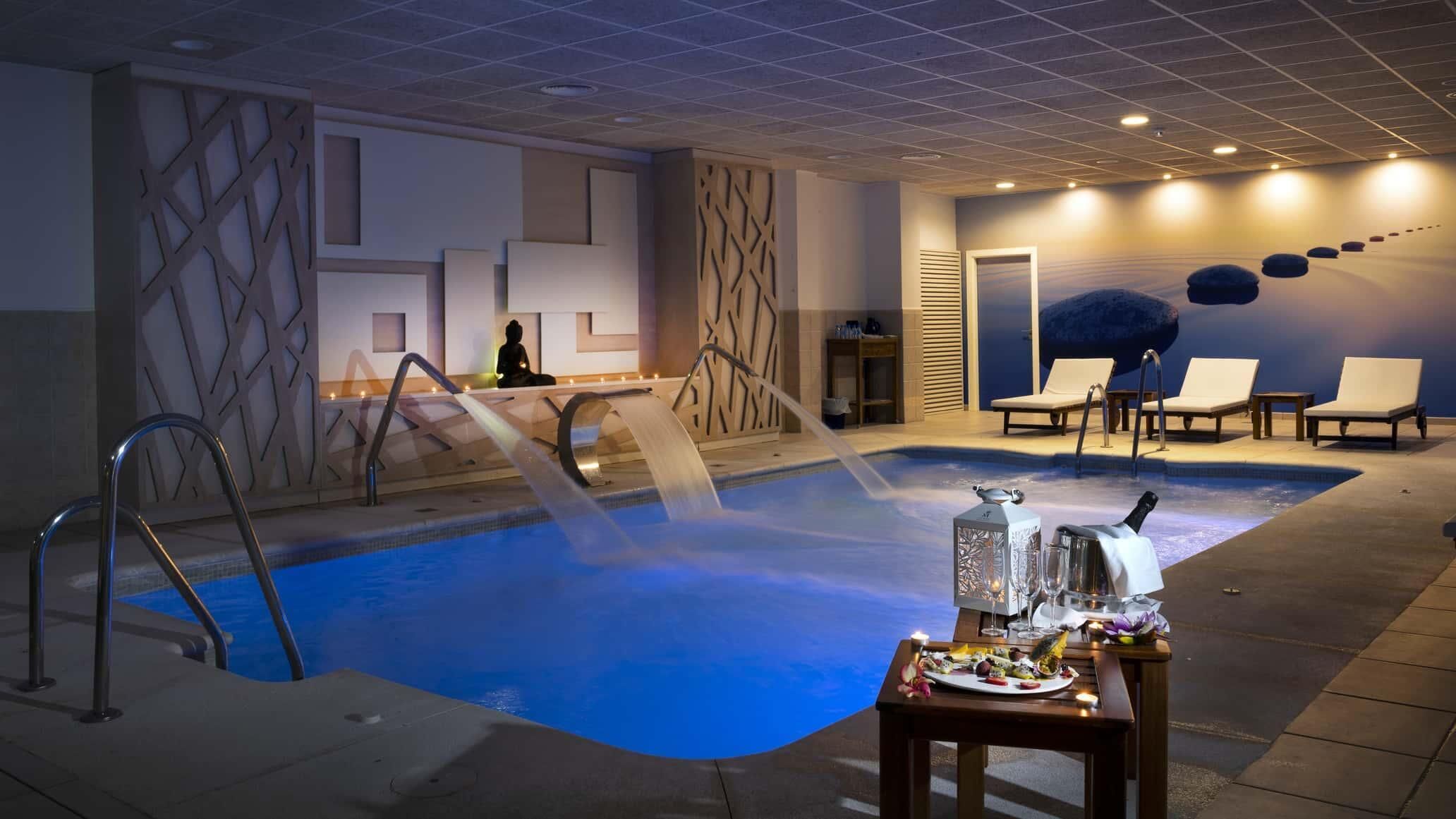 Zona de piscina con jacuzzi, sillas de descanso y una estatua de Buda.