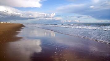 Una playa con una amplia orilla de arena y olas suaves.