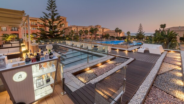 A rooftop bar with a pool, lounge chairs, and a bar cart. - Barceló Punta Umbría Mar (Punta Umbría)