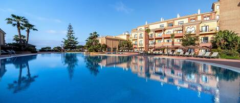 Alberca al aire libre, sombrillas en la alberca y camastros