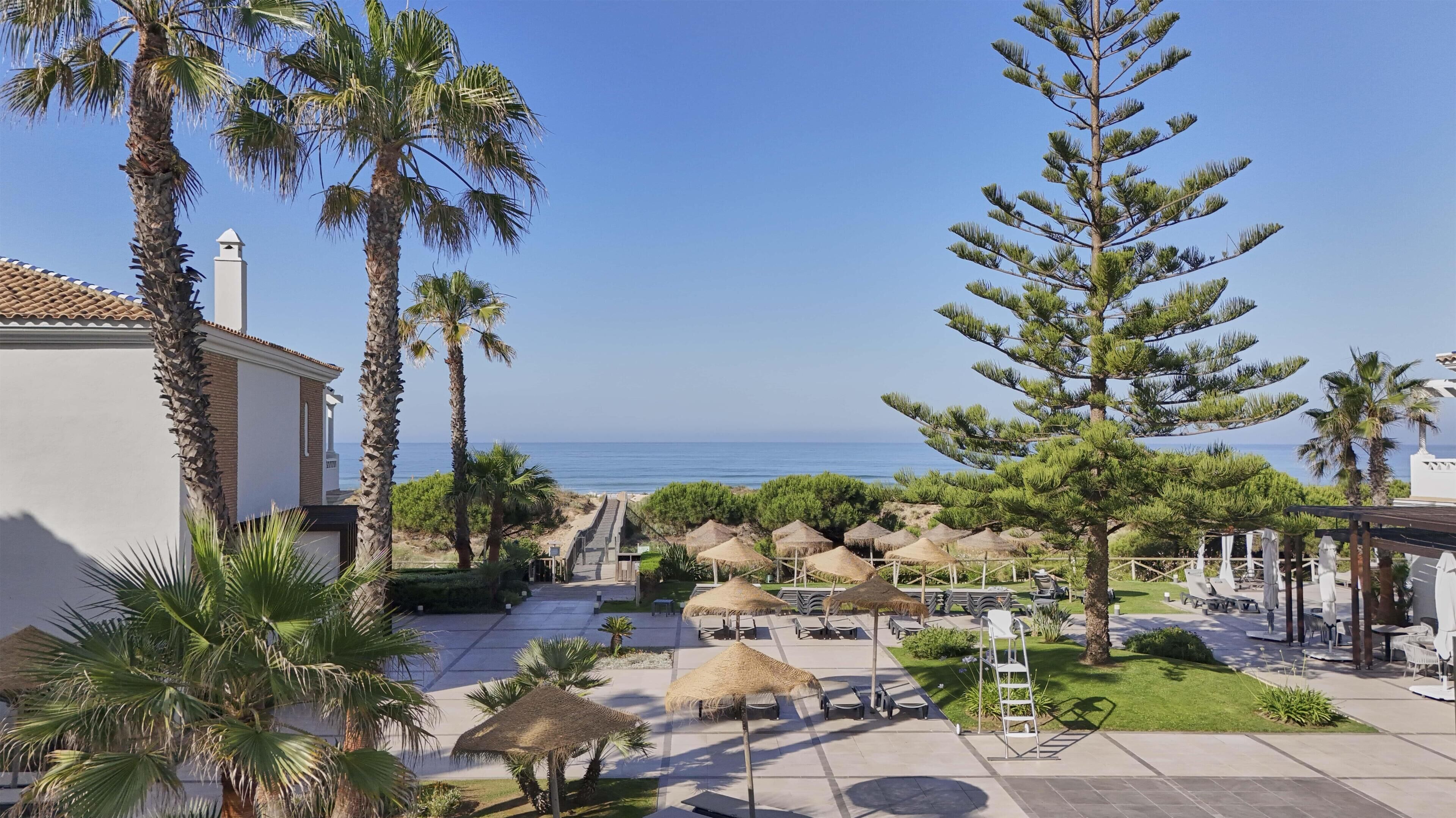 A resort with a pool area, outdoor seating, and a view of the sea.
