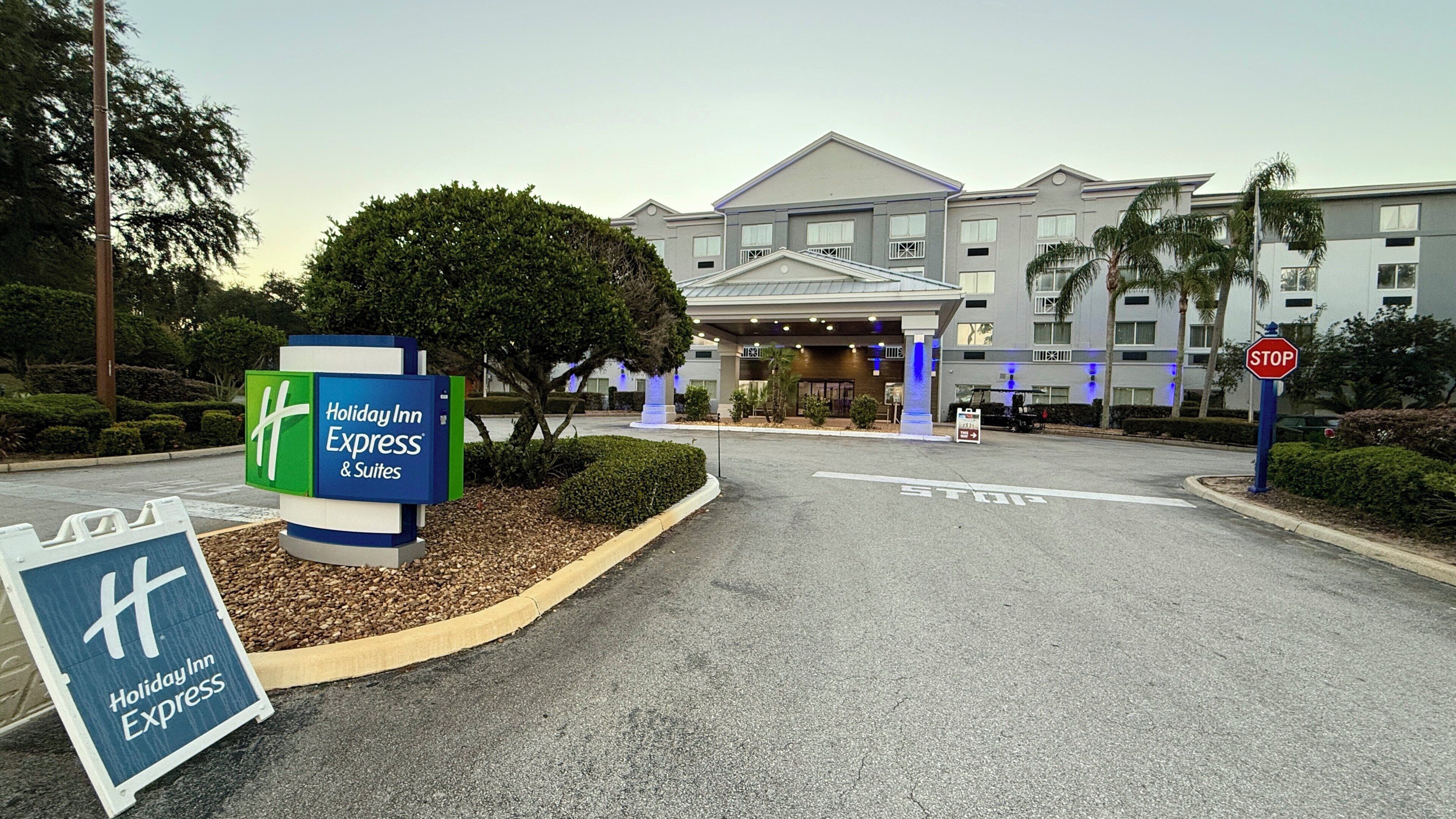 L’entrée d’un hôtel Holiday Inn Express & Suites, avec un panneau de signalisation, un panneau indicateur et une allée bien entretenue.