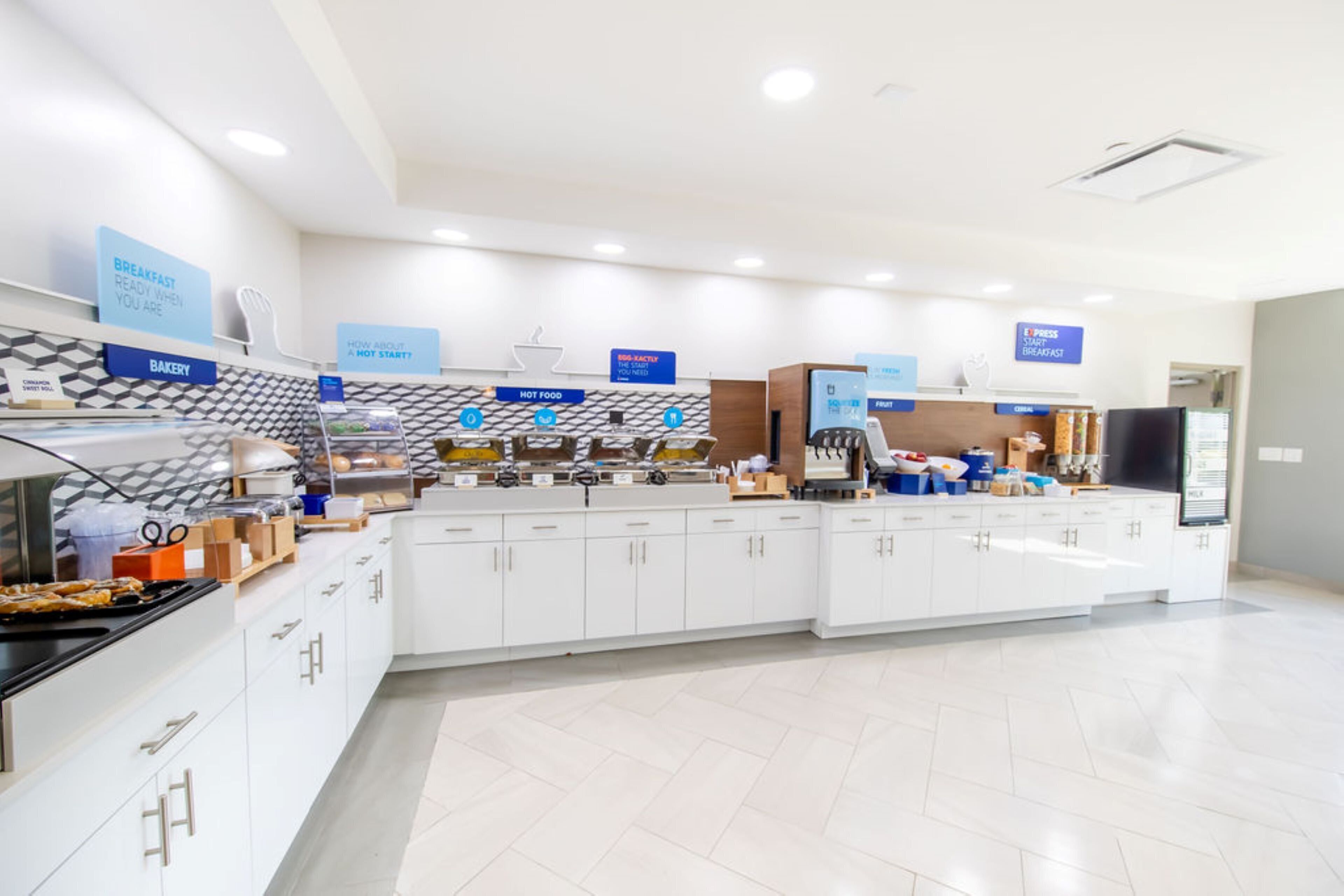 A modern breakfast area with a bakery section, a hot food station, and a self-service counter.