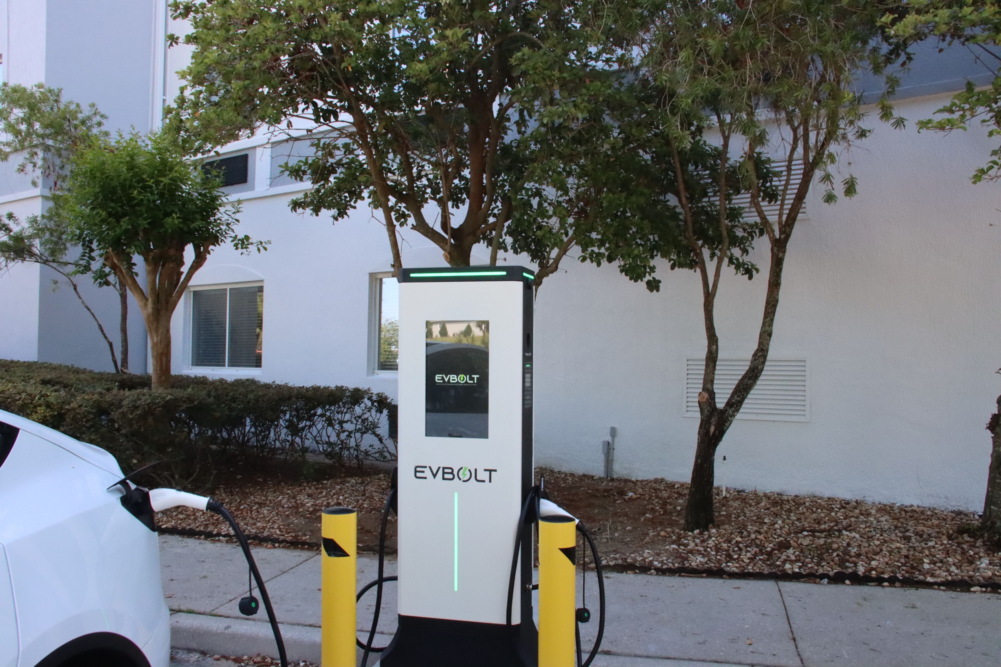 Eine EV Bolt Ladestation vor einem weißen Gebäude im Hintergrund.