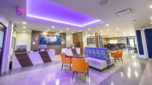 Un moderno vestíbulo de hotel con recepción, zona de estar y comedor.