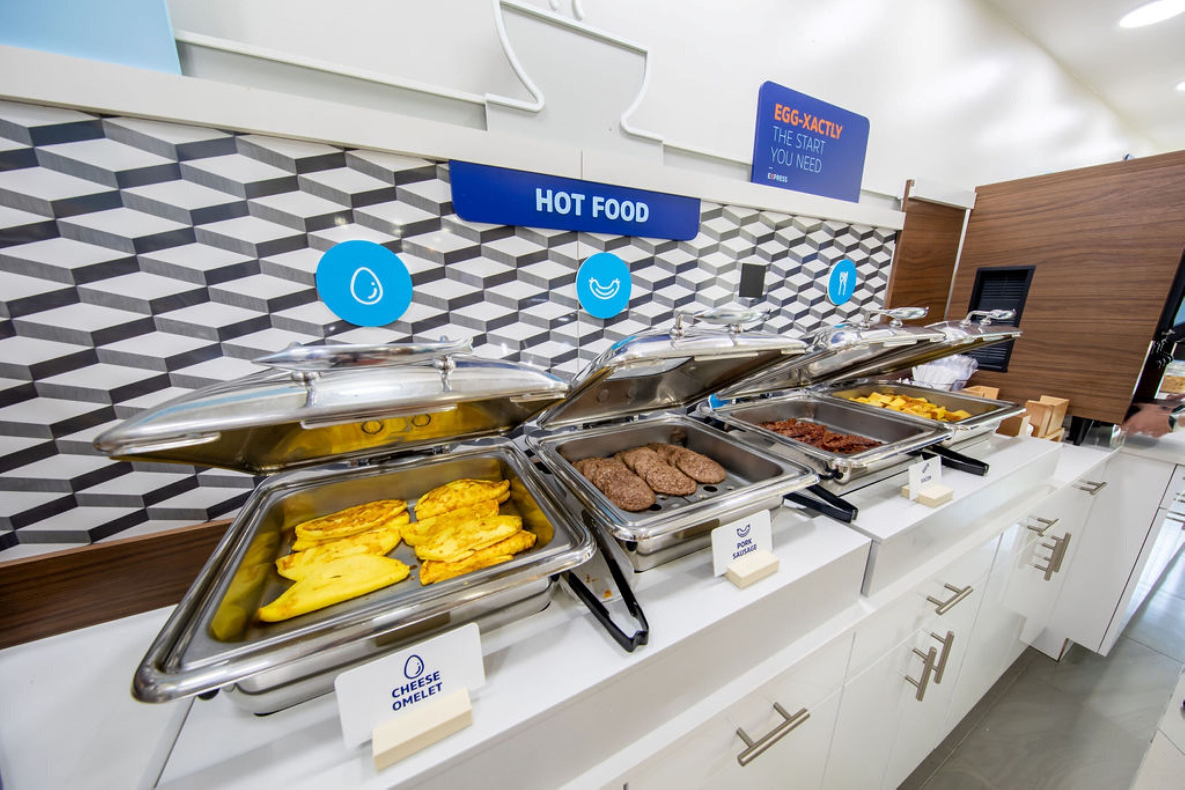 Ein Buffet mit ausgewiesenen Bereichen für warme Speisen, darunter Omeletts und weitere Gerichte.