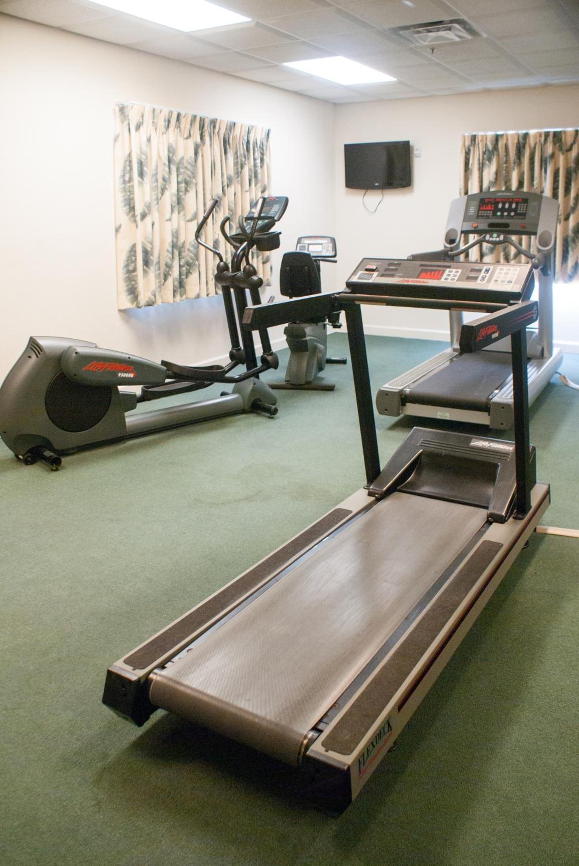 A fitness room with a treadmill, elliptical, and stationary bike.