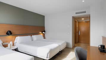 Una habitación de hotel con dos camas, un escritorio, una silla, una lámpara y una puerta.