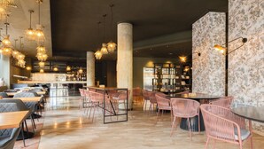 Un restaurante espacioso con techos altos, lámparas colgantes y una zona de bar.