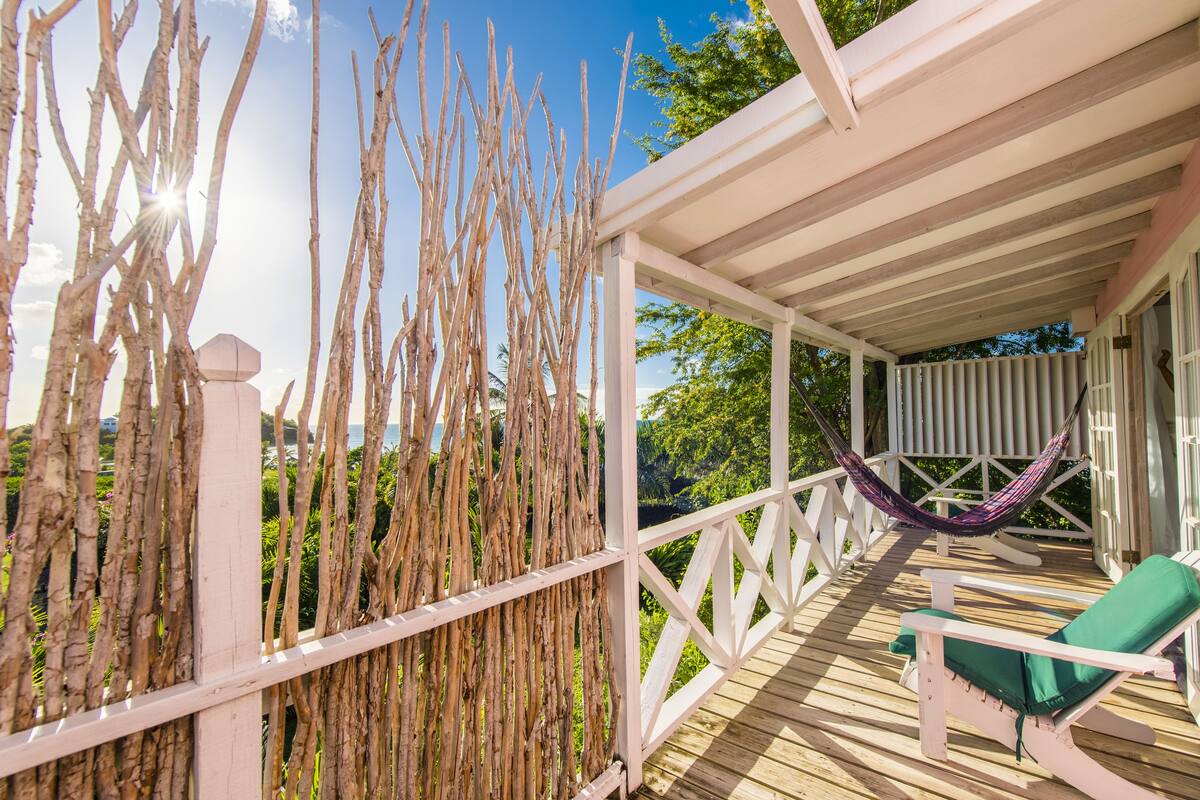 A wooden deck with a white railing, a hammock, and a green lounge chair.