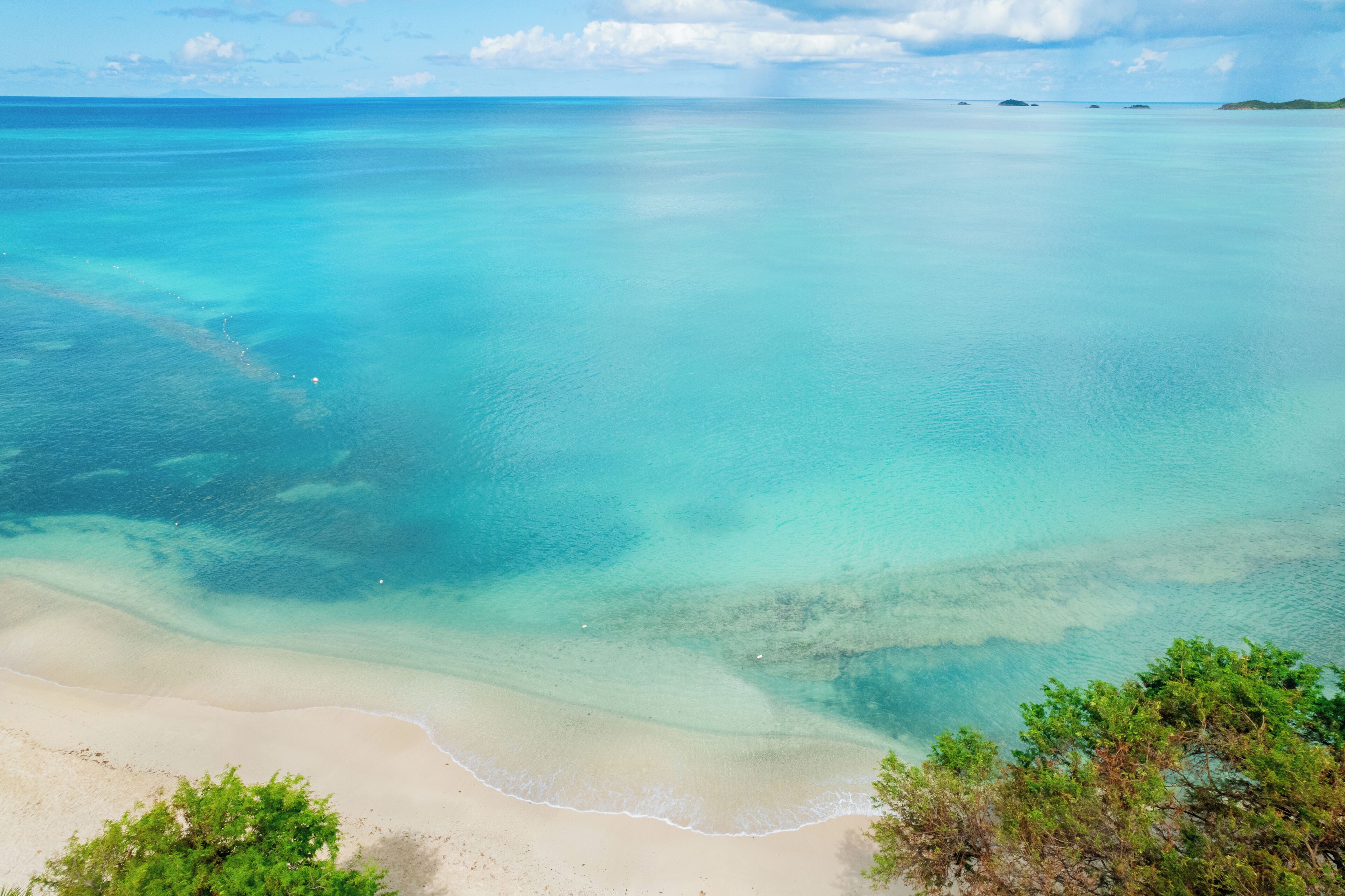 A beach with clear turquoise waters and a sandy shore.