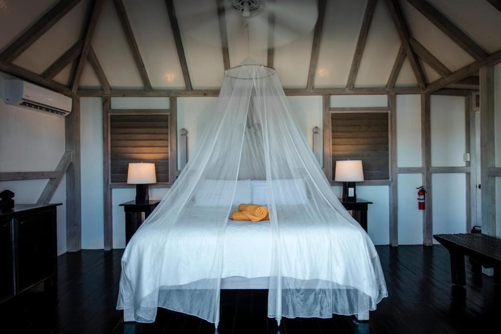 A room with a bed under a canopy, two bedside tables with lamps, and a fire extinguisher on the wall.