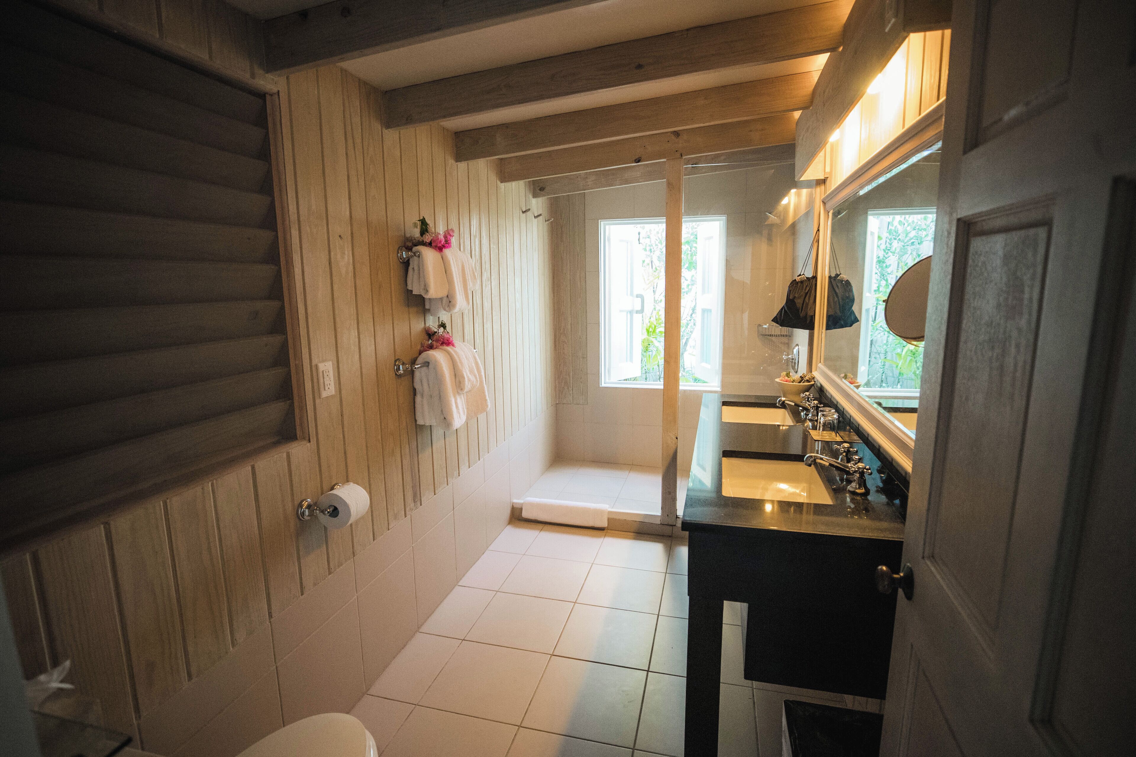 A bathroom with wooden paneling, a toilet, a sink with a mirror, and a shower area.