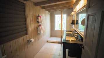 A bathroom with wooden paneling, a toilet, a sink with a mirror, and a shower area.