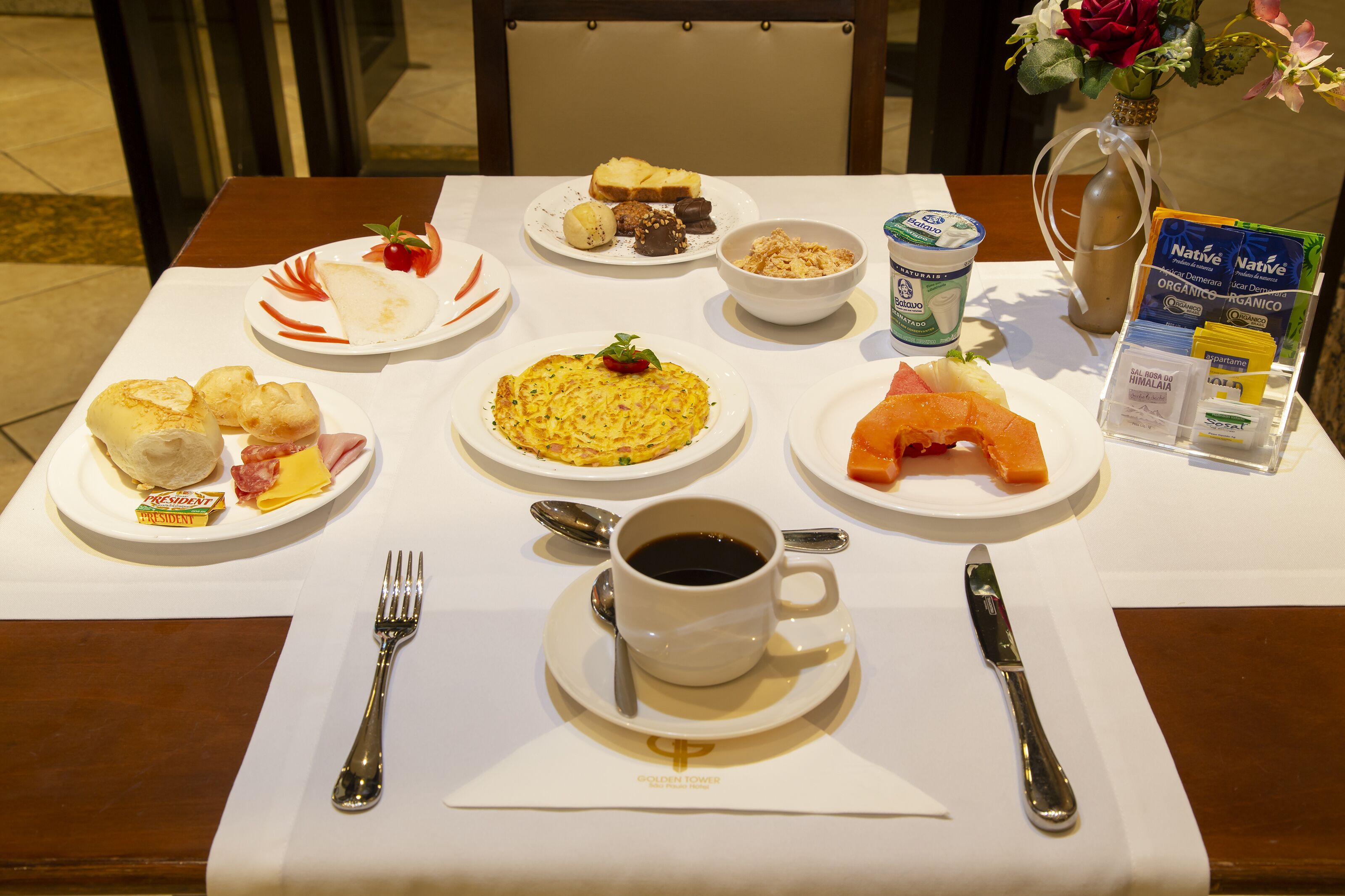 Uma mesa de café da manhã com pratos de comida, uma xícara de café e um cardápio.