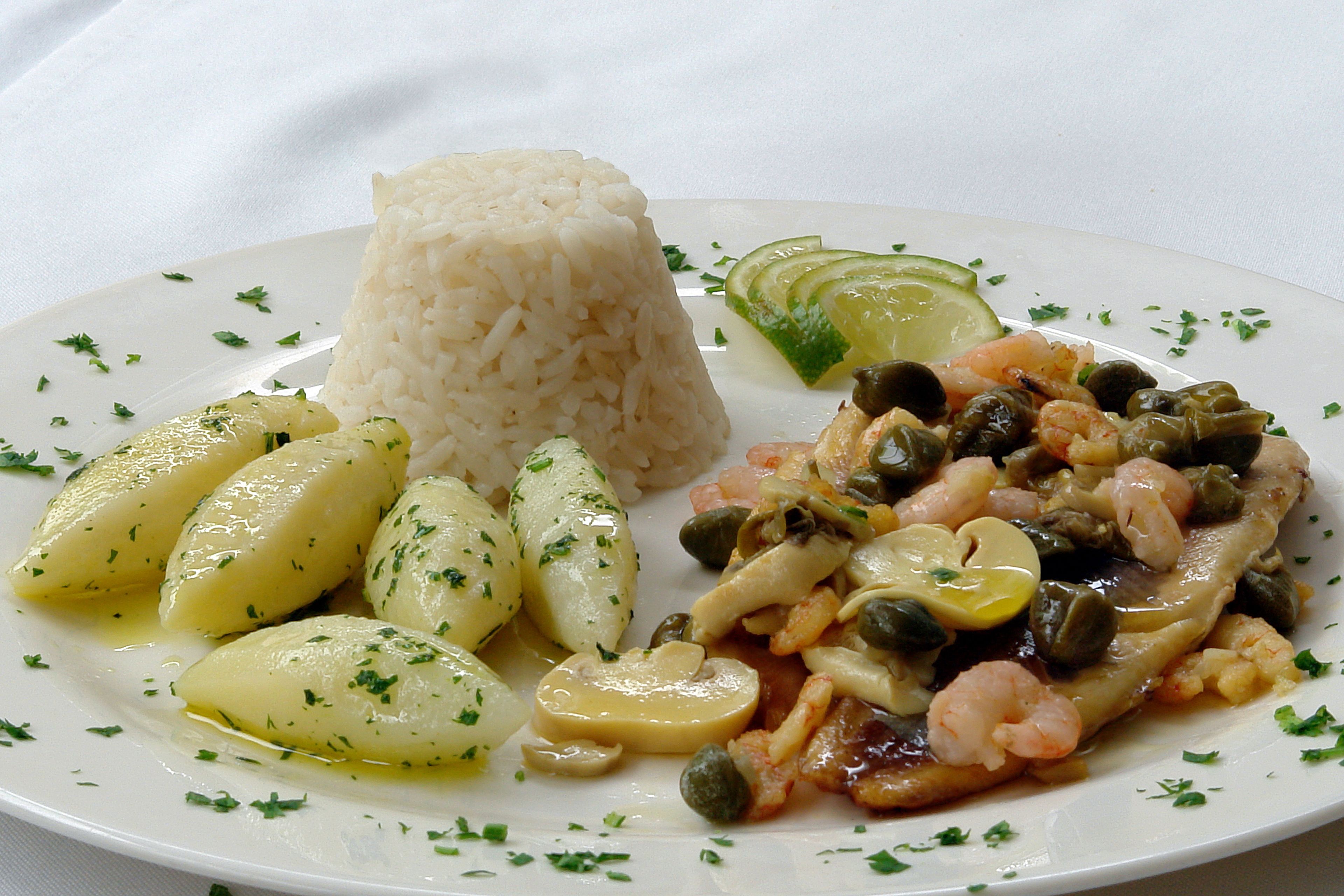 Un plato de arroz, patatas hervidas, camarones y alcaparras.