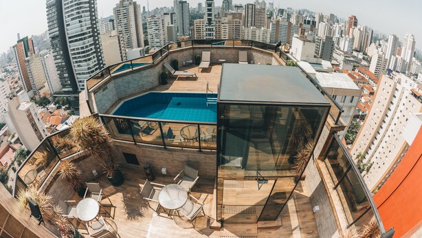 A rooftop terrace with a swimming pool, lounge chairs, and a glass-enclosed area. - Golden Tower Pinheiros by Fênix Hotéis (São Paulo)