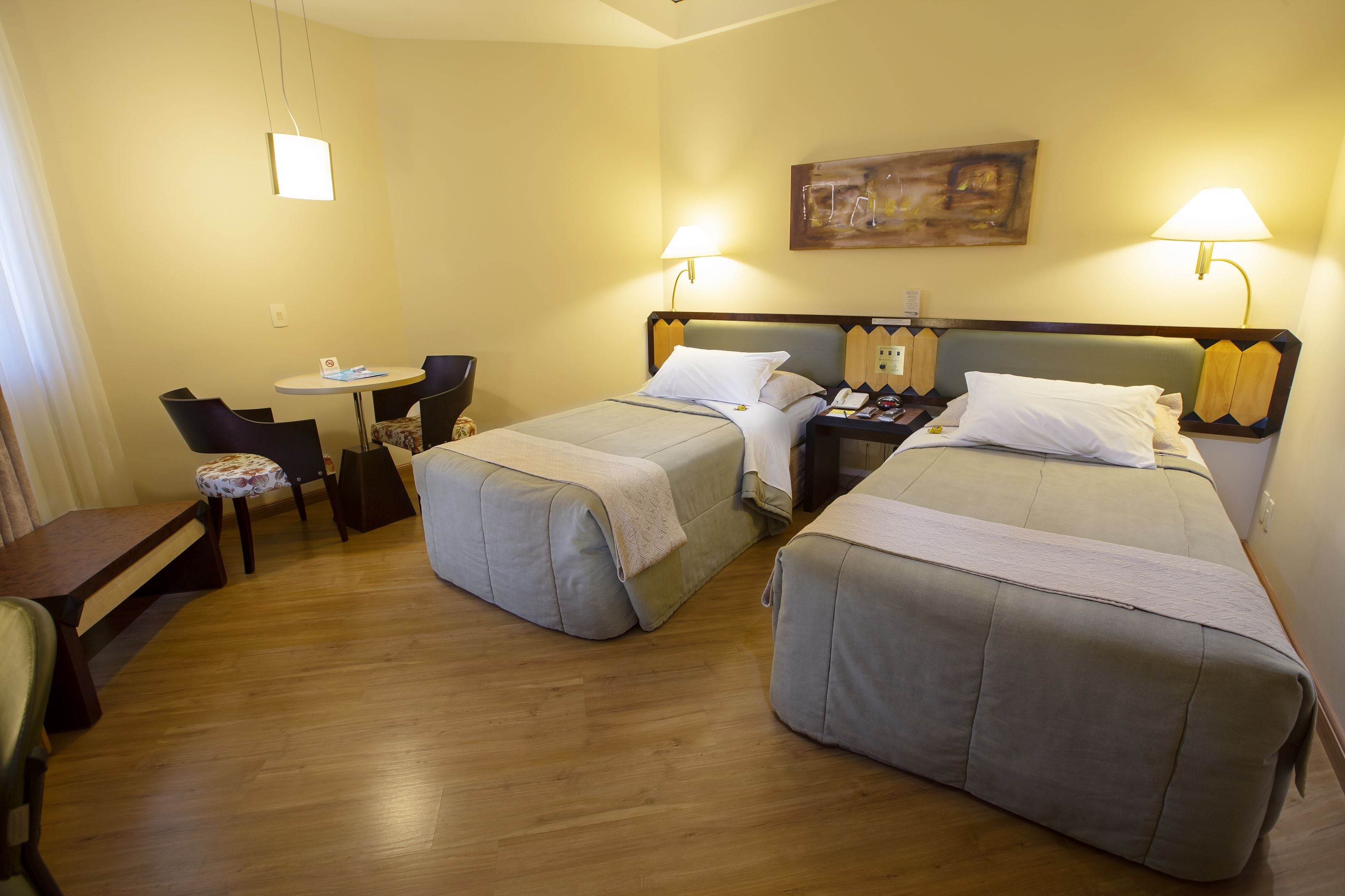 A hotel room with two beds, a desk, and a chair.