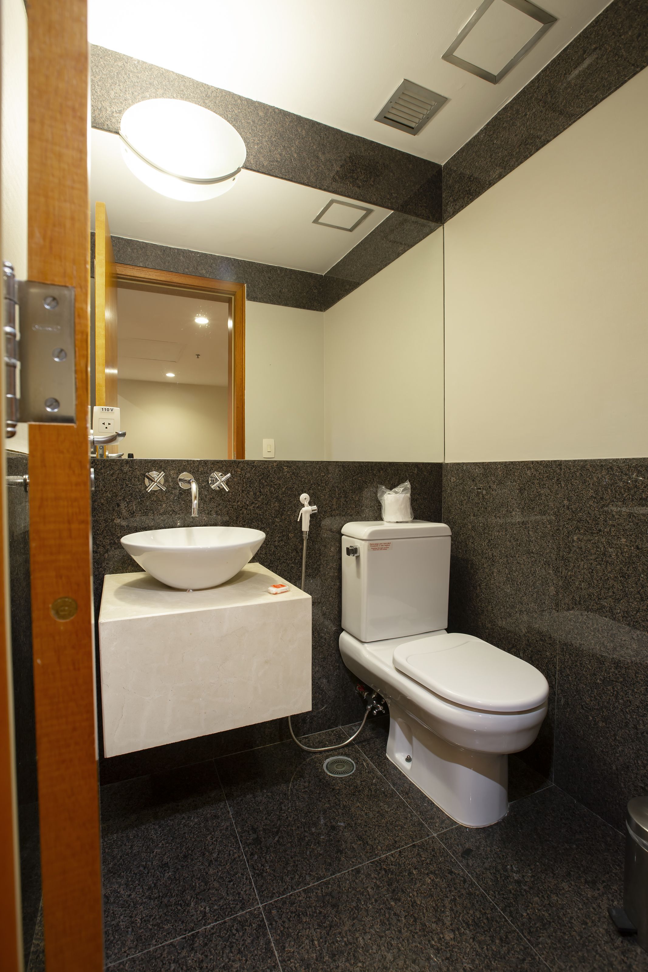A modern bathroom with a white sink, toilet, and a mirror above the sink.