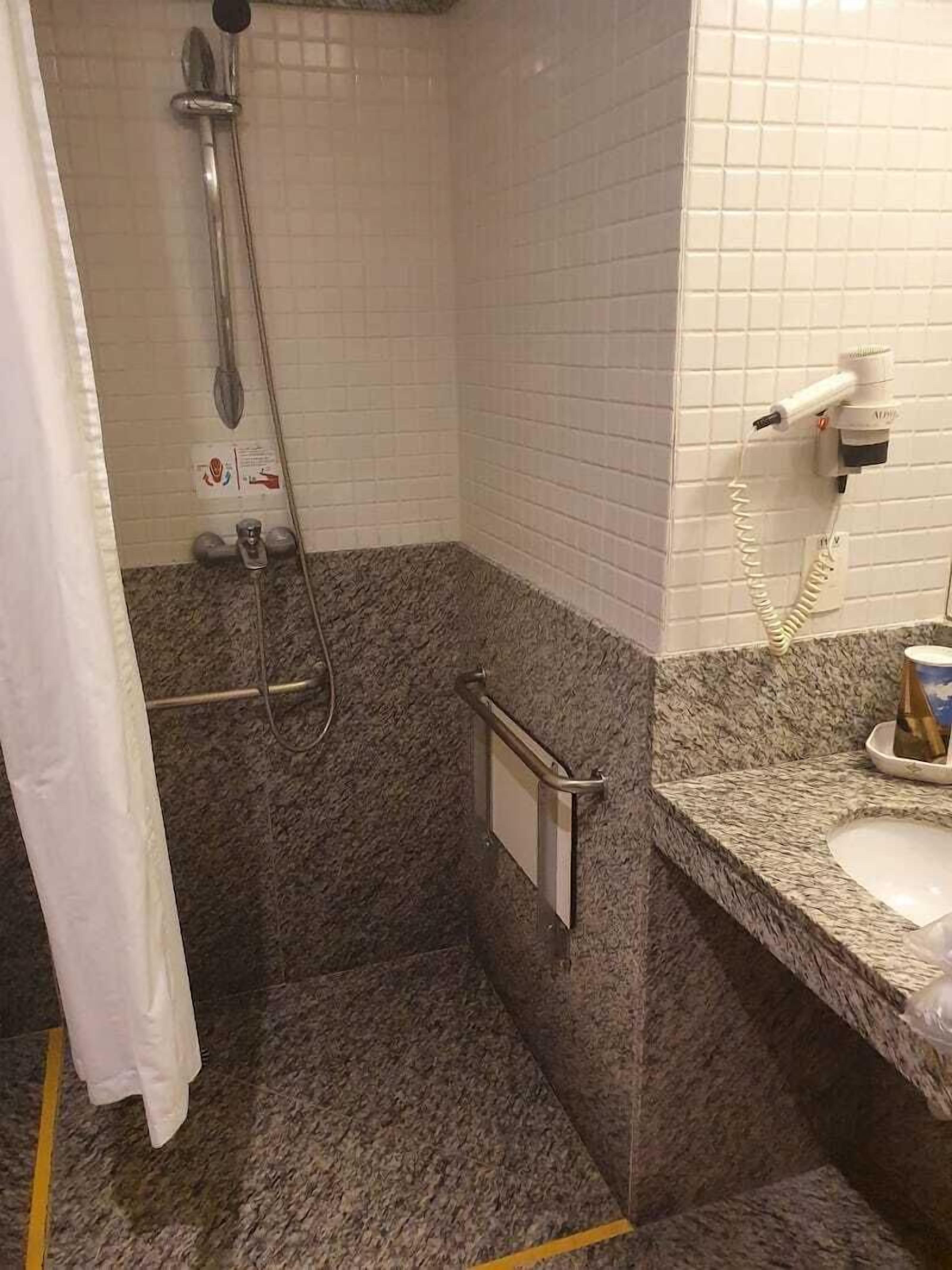 Ein Badezimmer mit Dusche, Handtrockner, Handtuchhalter und Waschbecken.