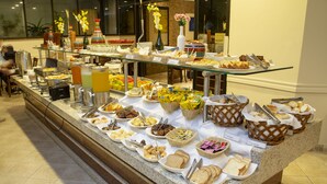 A buffet with various food items and utensils. - Golden Tower Pinheiros by Fênix Hotéis (São Paulo)