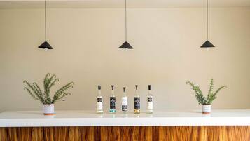 Un comptoir blanc avec cinq bouteilles de spiritueux et deux plantes en pot.