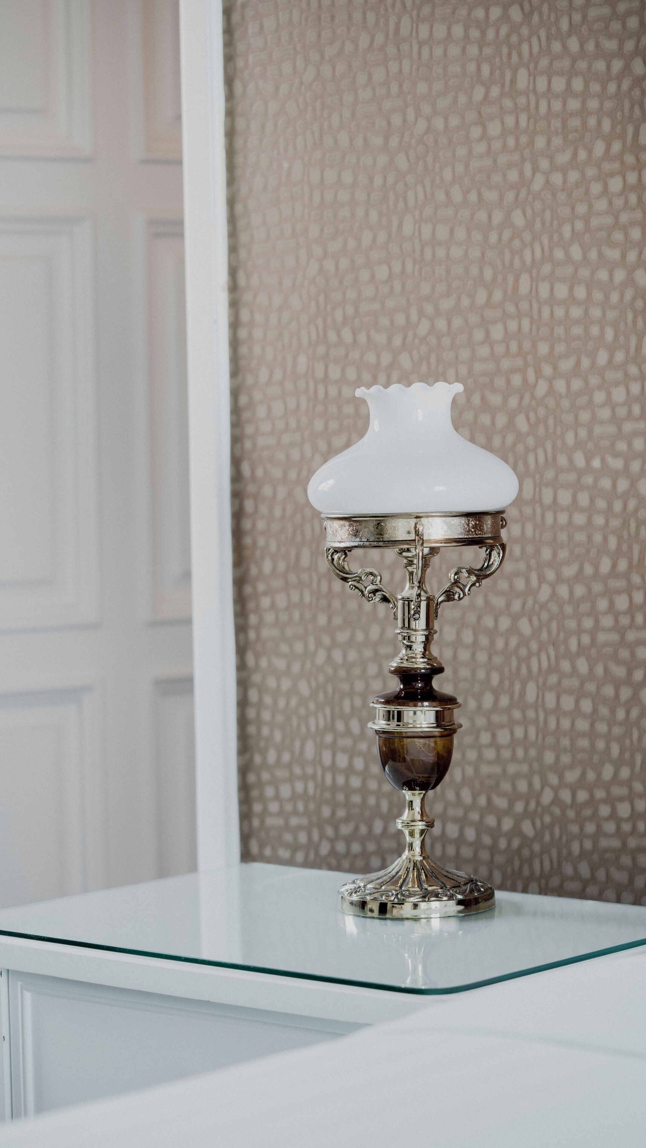 A white table with a decorative silver and glass candle holder.