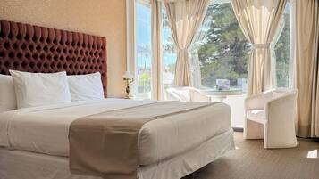 A hotel room with a large bed, a sitting area with a chair, and a view of the outdoors.