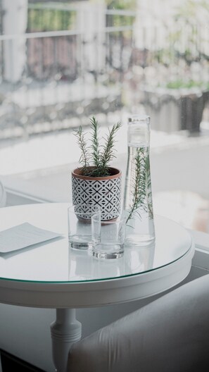 Una mesa redonda de vidrio con una planta en maceta, un florero de vidrio y dos vasos.